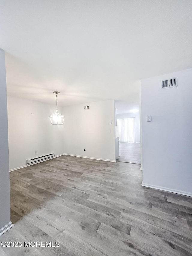 empty room featuring hardwood / wood-style flooring and a baseboard radiator