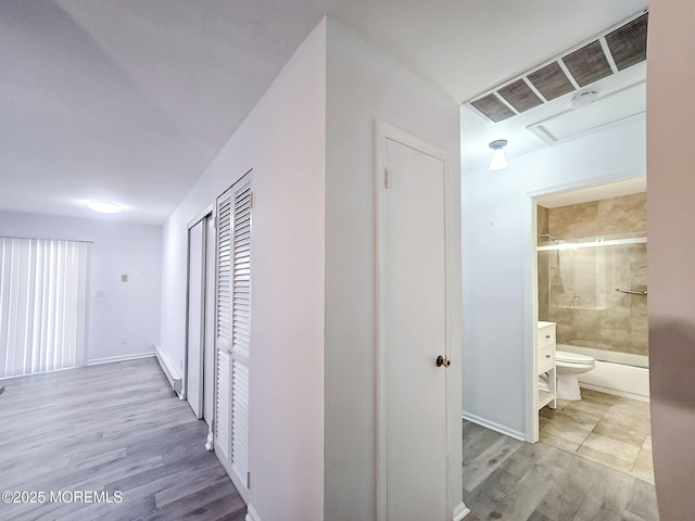 corridor with light hardwood / wood-style flooring and baseboard heating