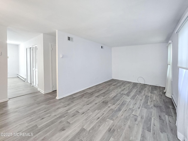 spare room featuring a baseboard radiator and light hardwood / wood-style floors