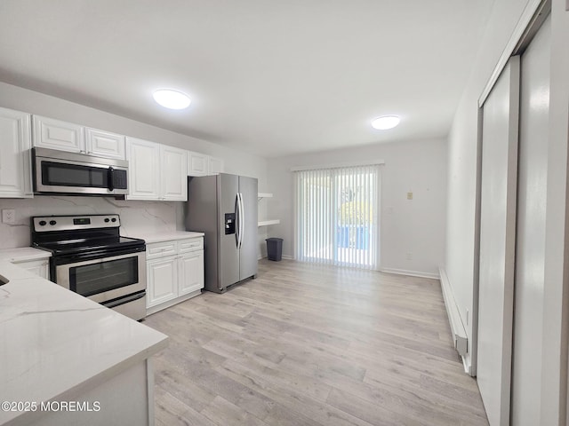 kitchen featuring light stone countertops, appliances with stainless steel finishes, white cabinets, and decorative backsplash