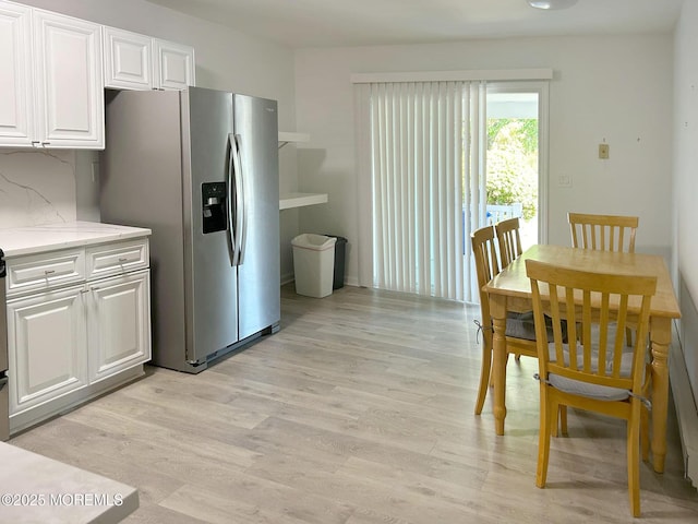 kitchen with white cabinetry, decorative backsplash, light hardwood / wood-style floors, and stainless steel fridge with ice dispenser