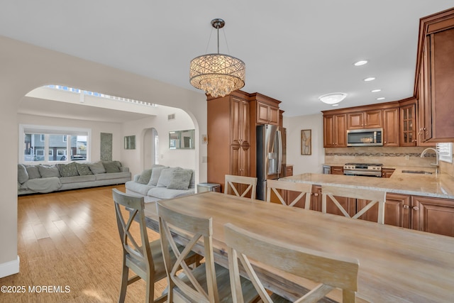 dining space featuring a notable chandelier, sink, and light wood-type flooring