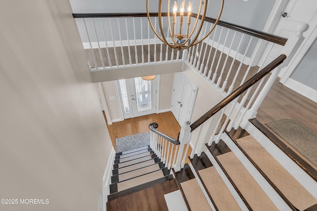 staircase with a notable chandelier and wood-type flooring