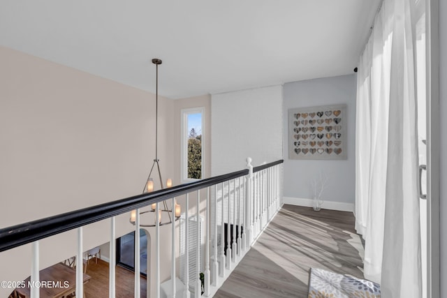 hallway with wood-type flooring and a chandelier