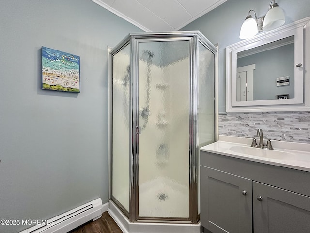 bathroom featuring walk in shower, tasteful backsplash, ornamental molding, vanity, and a baseboard heating unit