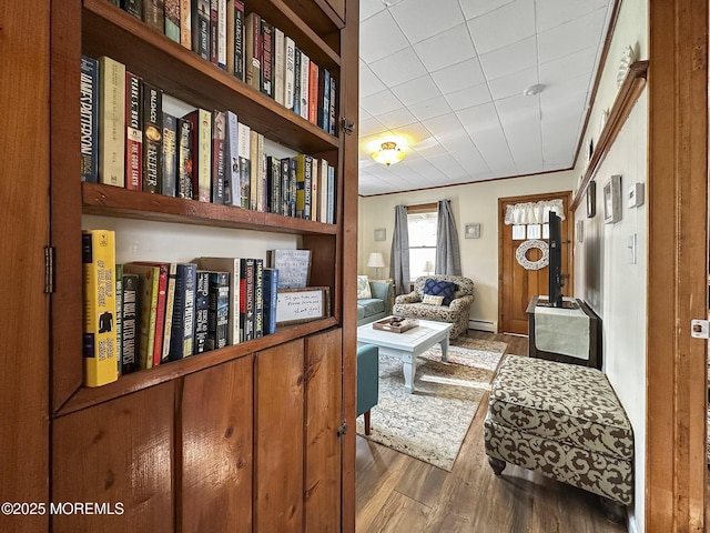 sitting room with baseboard heating, ornamental molding, and wood-type flooring