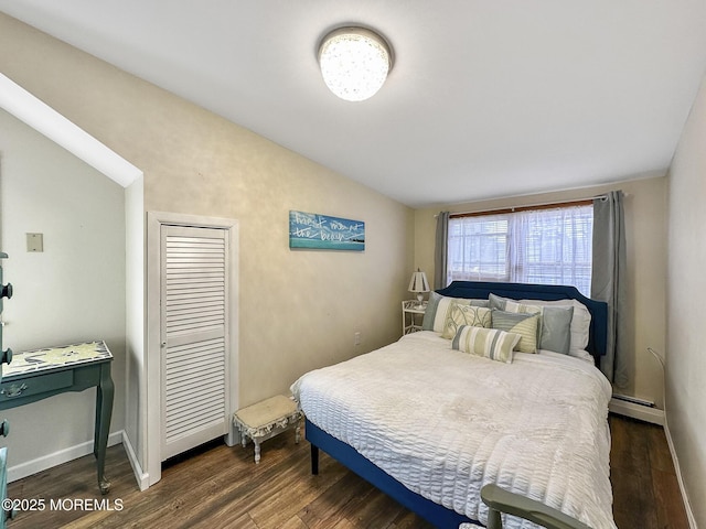 bedroom with dark hardwood / wood-style flooring, vaulted ceiling, and a baseboard heating unit