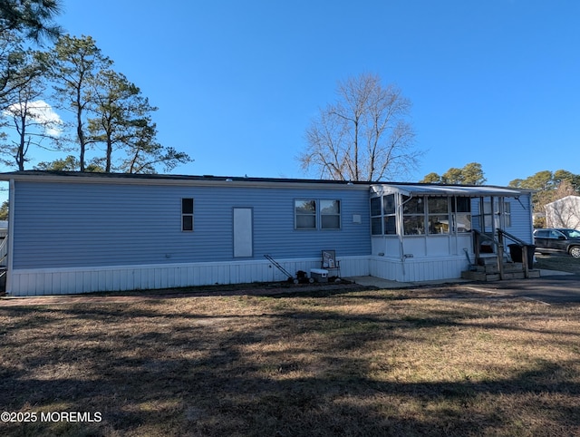 rear view of house featuring a yard and a sunroom