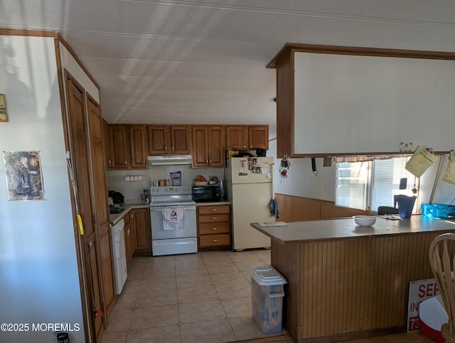 kitchen featuring light tile patterned flooring, wood walls, white appliances, and kitchen peninsula