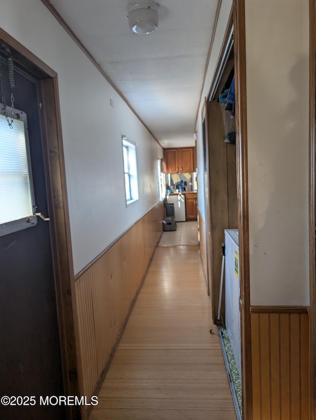 corridor with light hardwood / wood-style flooring and wood walls