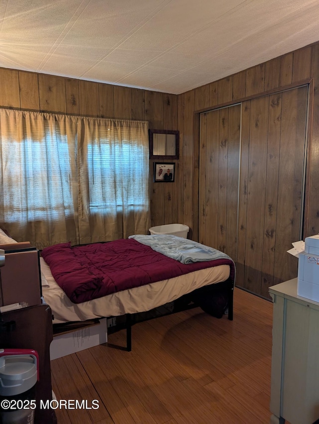 bedroom featuring hardwood / wood-style floors, wood walls, and a closet