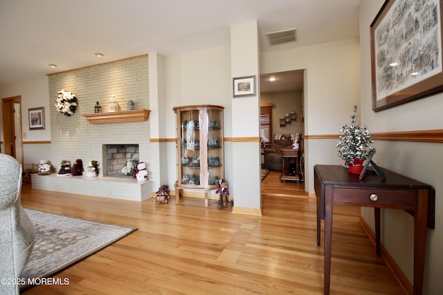 living room with a brick fireplace and light wood-type flooring