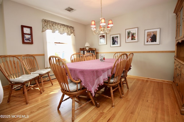 dining space with light hardwood / wood-style flooring and a notable chandelier