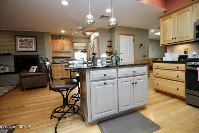 kitchen featuring pendant lighting, a breakfast bar area, stainless steel appliances, a center island, and light hardwood / wood-style floors