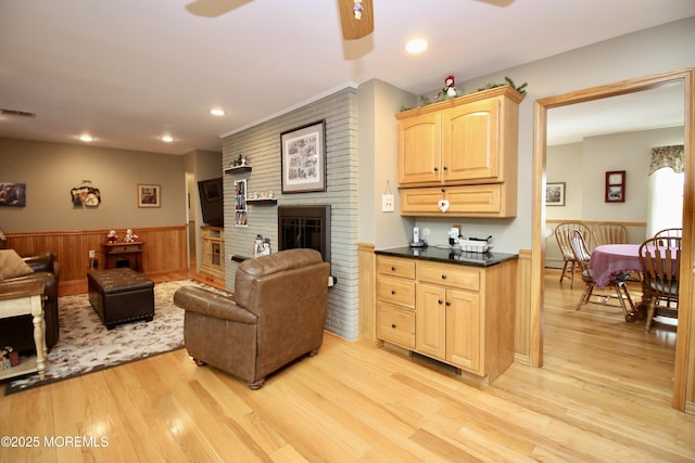 living room featuring a brick fireplace, ceiling fan, and light hardwood / wood-style flooring