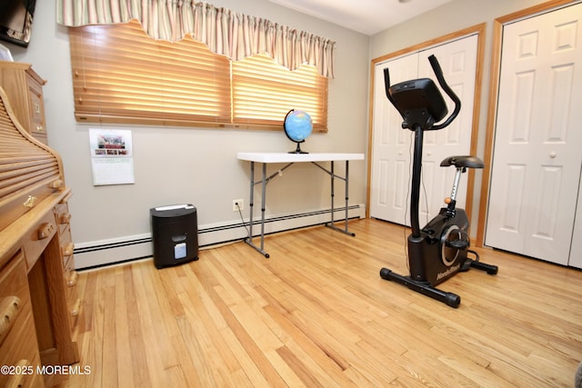 workout room featuring a baseboard heating unit and wood-type flooring