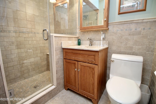 bathroom featuring vanity, toilet, a shower with door, and tile walls