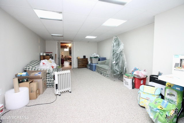 basement featuring radiator, carpet floors, and a paneled ceiling