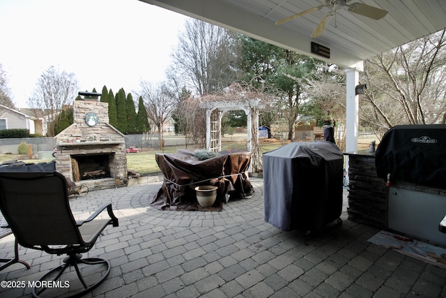 view of patio / terrace featuring area for grilling, ceiling fan, and an outdoor stone fireplace