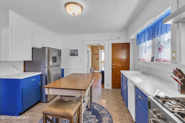 kitchen featuring sink, white cabinets, range, stainless steel refrigerator with ice dispenser, and blue cabinetry