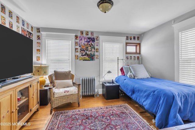 bedroom featuring multiple windows, radiator, and hardwood / wood-style floors