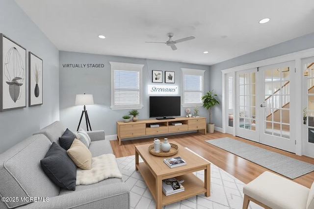 living room with french doors, ceiling fan, and light wood-type flooring