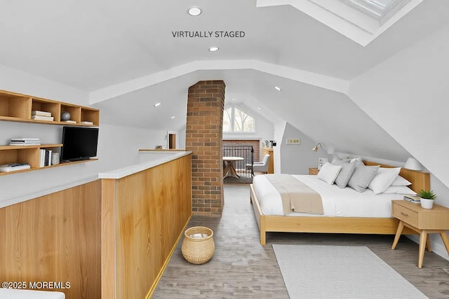 bedroom with lofted ceiling with skylight and hardwood / wood-style floors