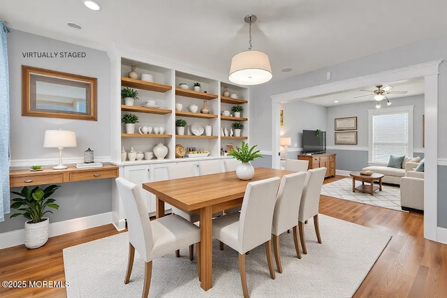 dining room with ceiling fan, built in features, and light wood-type flooring