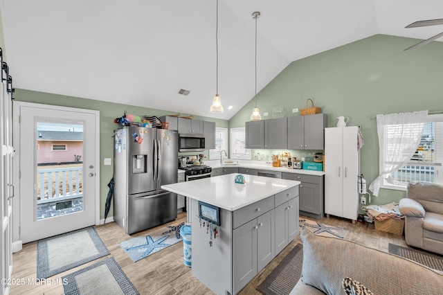 kitchen with a kitchen island, decorative light fixtures, sink, stainless steel appliances, and a barn door