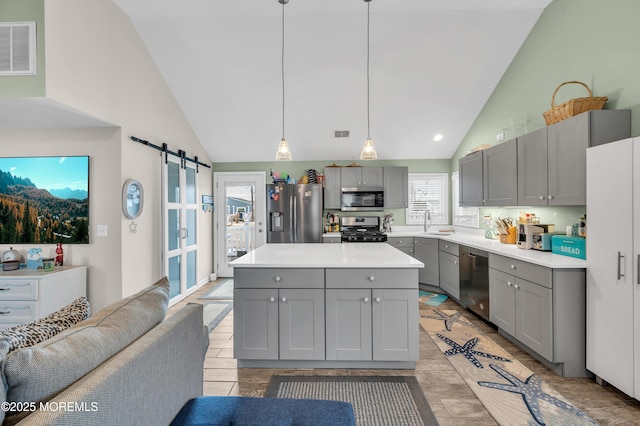 kitchen with sink, gray cabinets, pendant lighting, stainless steel appliances, and a barn door