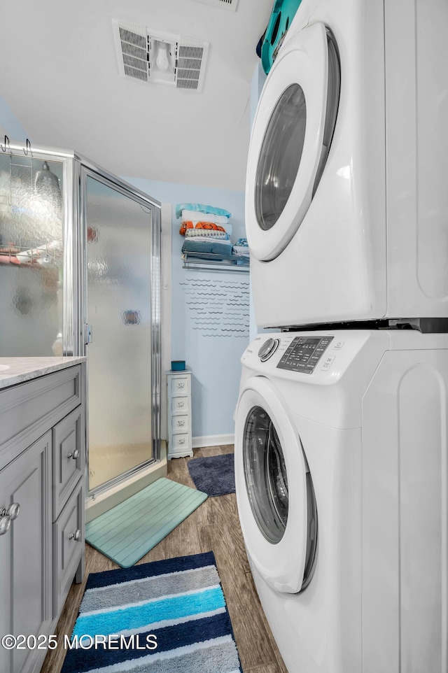 washroom with dark wood-type flooring and stacked washing maching and dryer