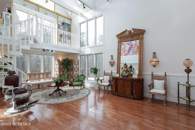 sitting room with hardwood / wood-style flooring and a towering ceiling