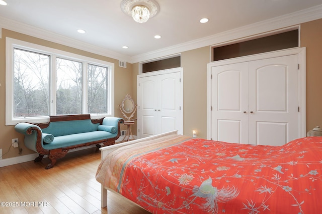 bedroom featuring crown molding, hardwood / wood-style flooring, and two closets