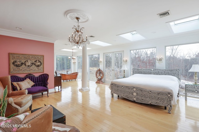 bedroom featuring crown molding, a chandelier, light hardwood / wood-style floors, and ornate columns