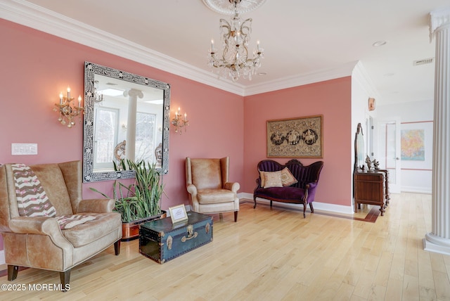 living area with crown molding, a chandelier, and hardwood / wood-style floors