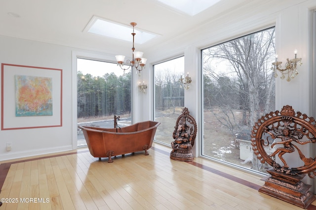 sunroom / solarium featuring a notable chandelier and a skylight