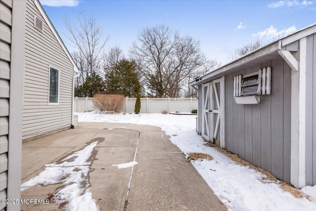 yard layered in snow featuring a patio and an outdoor structure