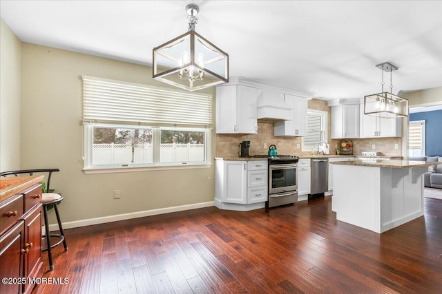 kitchen featuring stainless steel appliances, decorative light fixtures, light stone countertops, and white cabinets