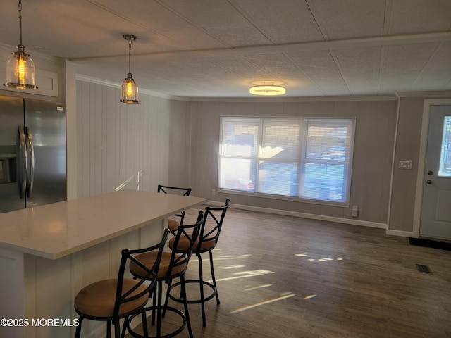 kitchen featuring ornamental molding, a kitchen breakfast bar, dark hardwood / wood-style flooring, pendant lighting, and white cabinets