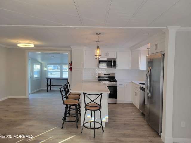 kitchen featuring stainless steel appliances, a kitchen island, hanging light fixtures, and white cabinets