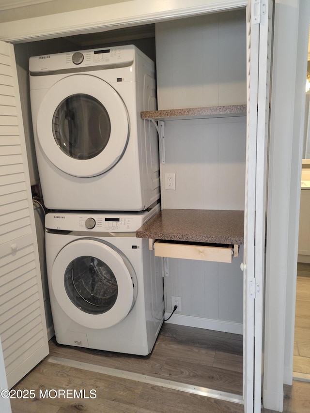 clothes washing area featuring stacked washer / dryer and hardwood / wood-style flooring