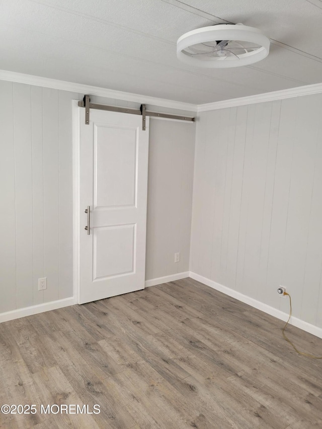 unfurnished room featuring hardwood / wood-style flooring, crown molding, and a barn door