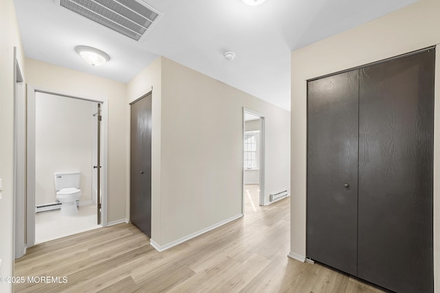 hall with a baseboard heating unit and light hardwood / wood-style floors