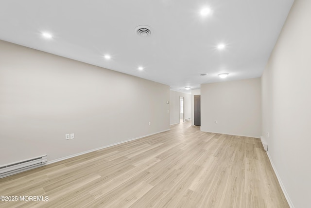 unfurnished room featuring a baseboard heating unit and light wood-type flooring