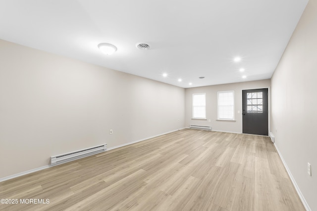 empty room featuring a baseboard heating unit and light hardwood / wood-style floors