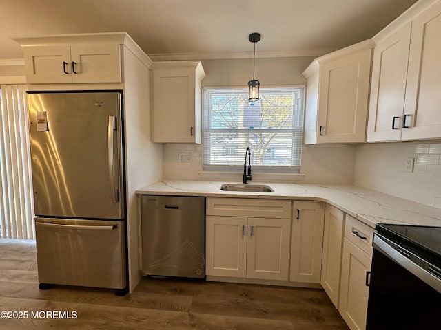 kitchen featuring light stone counters, sink, stainless steel appliances, and hanging light fixtures