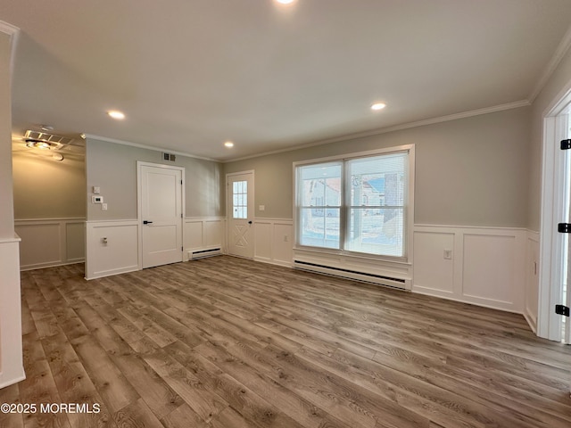 unfurnished living room featuring crown molding, hardwood / wood-style floors, and baseboard heating