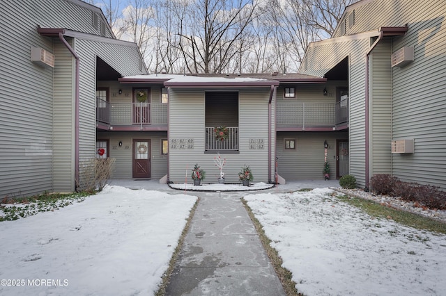 snow covered property entrance featuring a wall mounted air conditioner