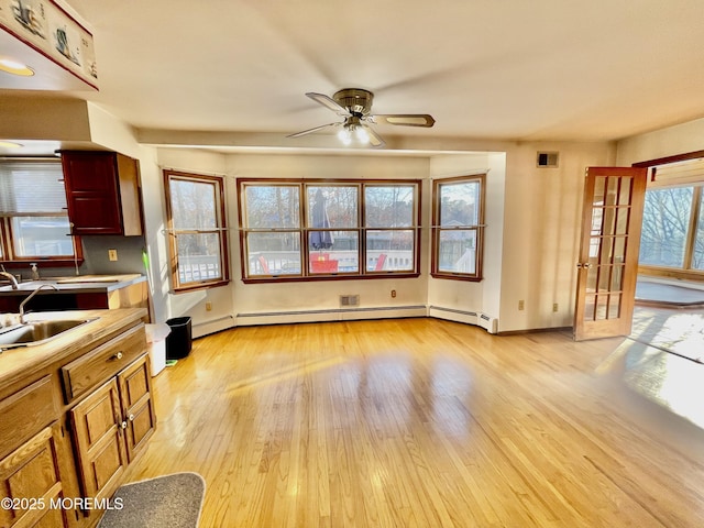 kitchen featuring baseboard heating, ceiling fan, light hardwood / wood-style floors, and sink