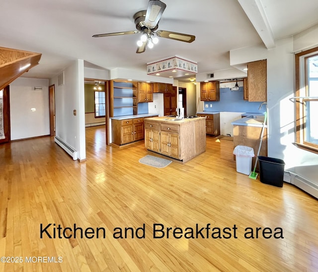 kitchen with sink, a baseboard heating unit, beam ceiling, a center island, and light hardwood / wood-style floors